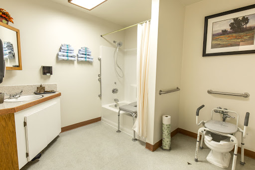 An accessible bathroom designed for individuals with mobility challenges, featuring safety bars and a shower bench.