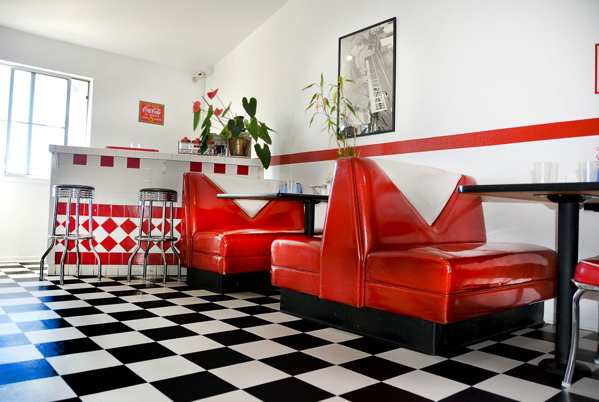 A retro diner interior with red booths and a classic black and white checkered floor.
