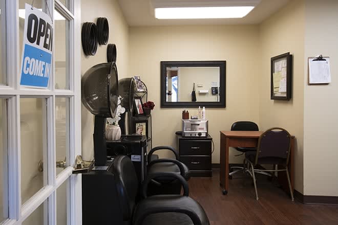 An interior view of a salon with chairs, a mirror, and hair dryers.