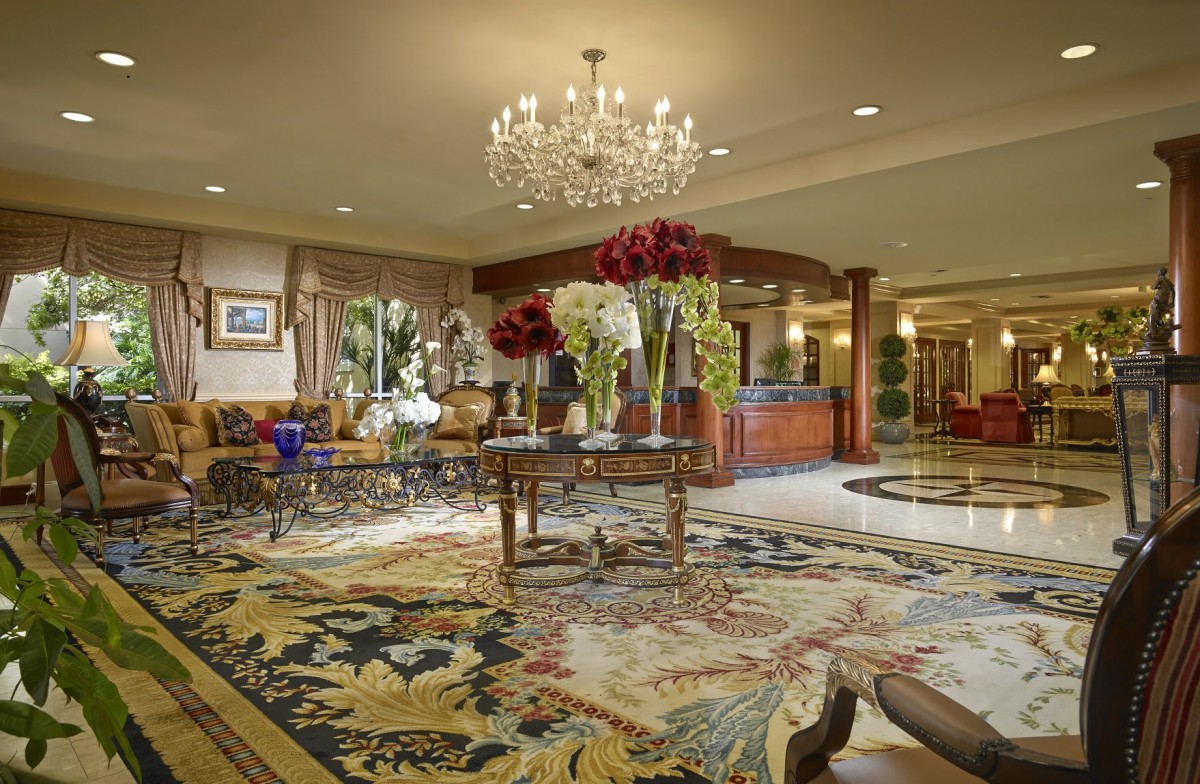 A luxurious hotel lobby with elegant decor, featuring a grand chandelier and floral arrangements.
