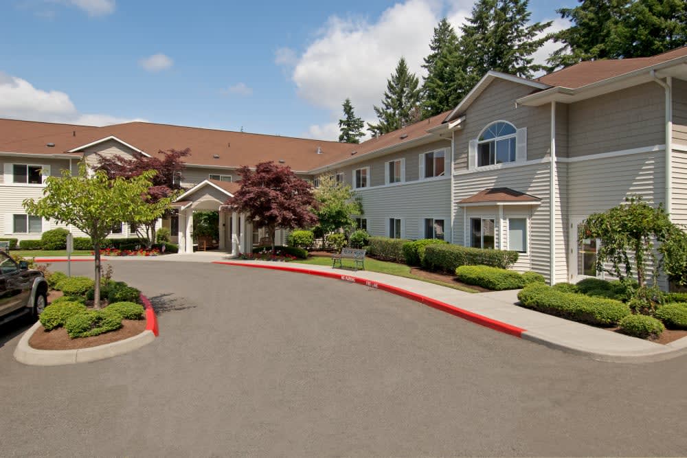 A spacious residential building with neatly landscaped surroundings and a driveway, set under a partly cloudy sky.