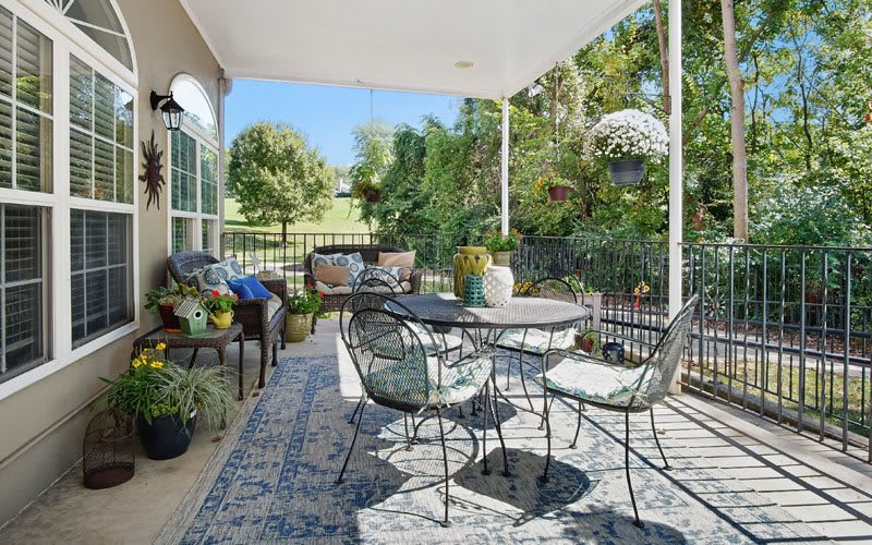 A cozy patio with outdoor furniture and lush plants on a sunny day.