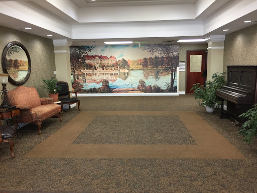 A spacious lobby featuring a serene mural, comfortable seating, and lush greenery.
