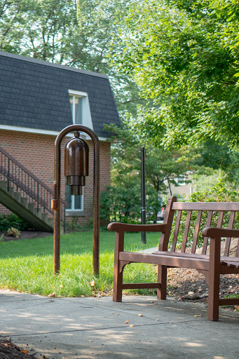 A peaceful outdoor setting featuring a wooden bench and decorative wind chimes, perfect for enjoying a quiet moment.