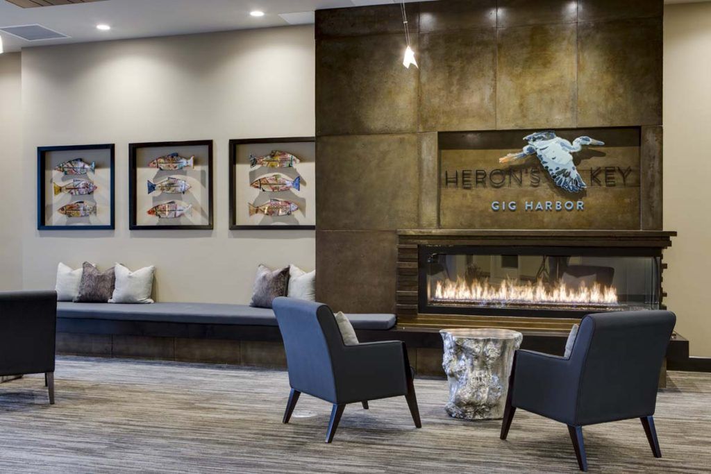 A modern hotel lobby featuring a cozy seating area with a fireplace and decorative artwork.