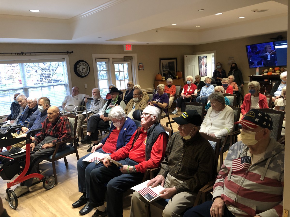 A group of elderly individuals seated indoors, attending a meeting or community event.