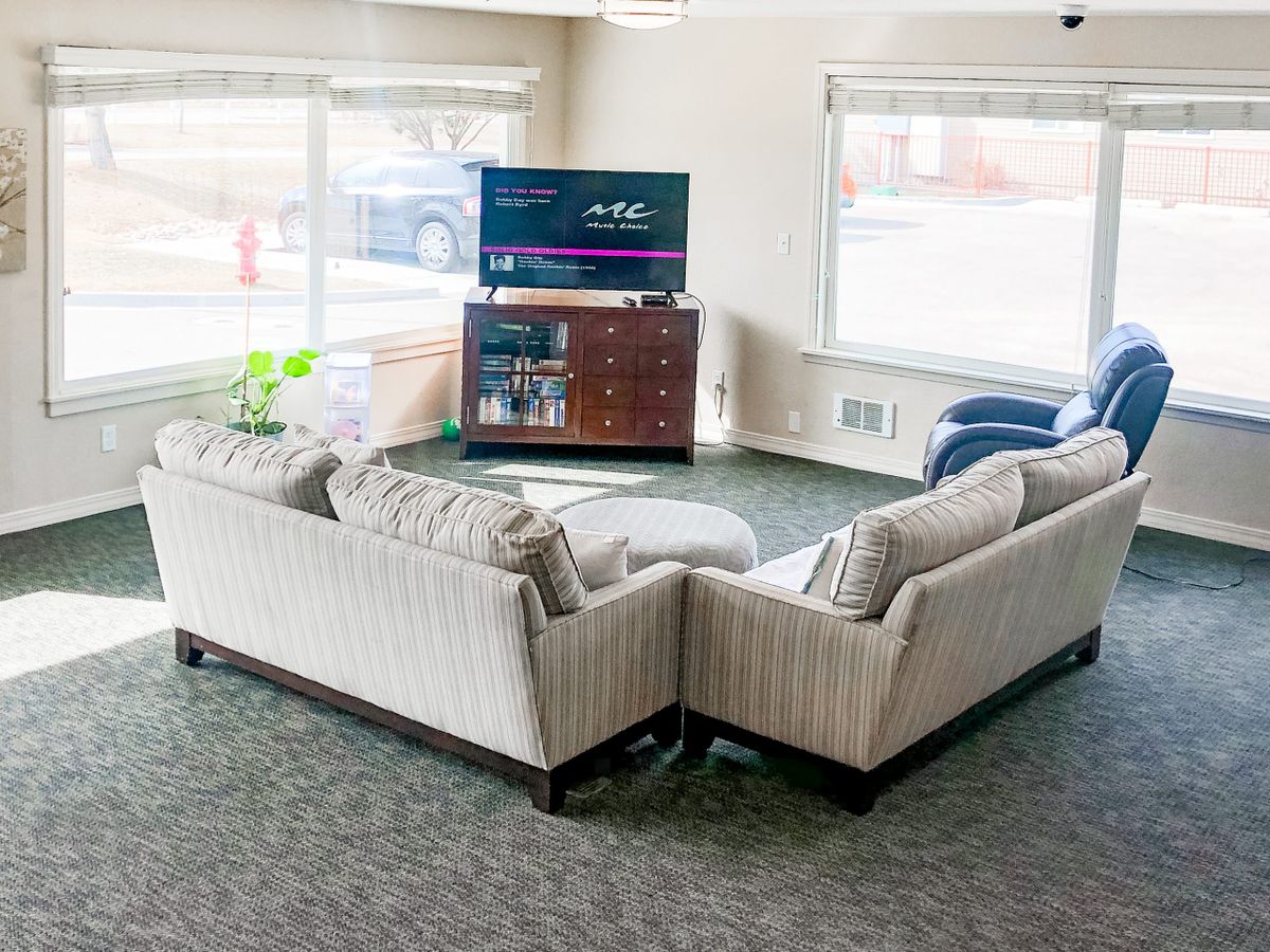 A cozy living room with a large sectional sofa, TV, and abundant natural light from large windows.