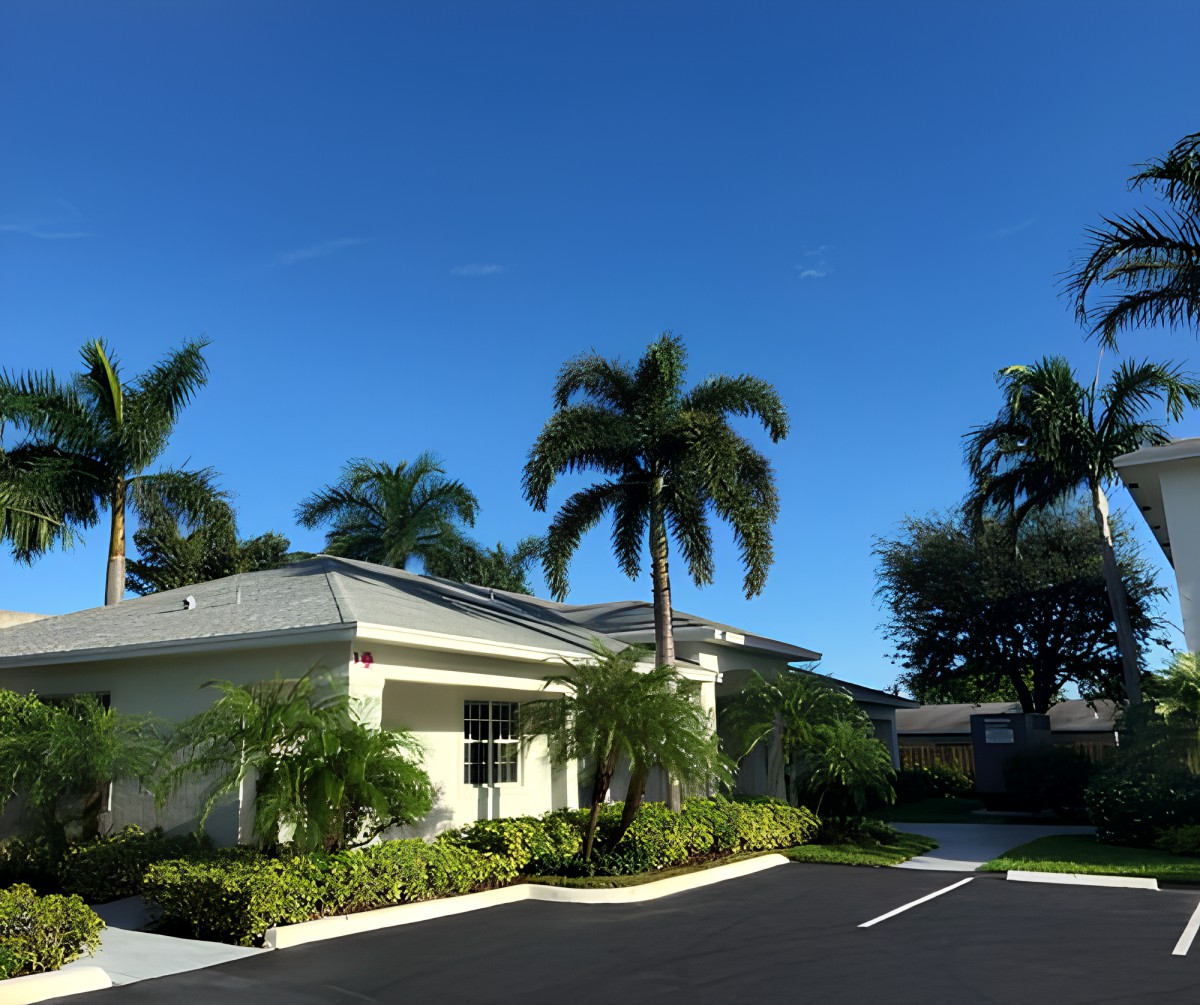 A suburban building surrounded by palm trees under a clear blue sky.