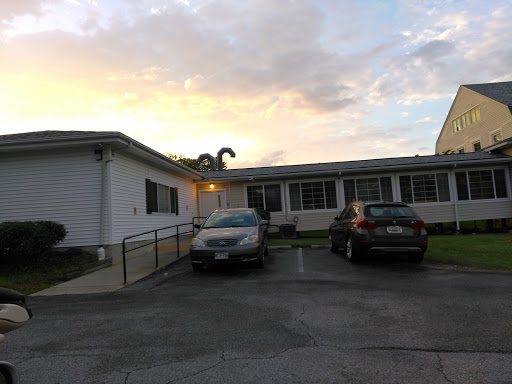 Evening view of a residential building with parked cars and a beautiful sky.