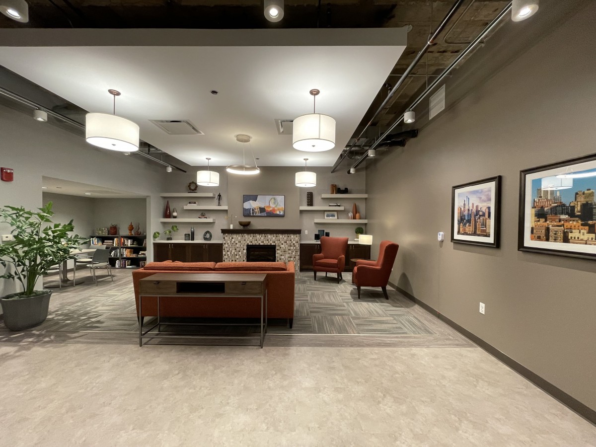 A modern office reception area with a desk, comfortable seating, and stylish lighting.