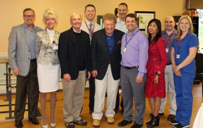 A group of professionals standing together and smiling for a photo indoors.