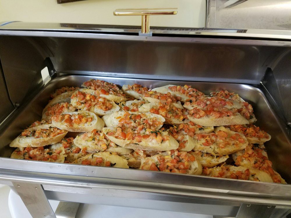 A tray of cooked chicken breast topped with a mix of vegetables ready for serving.