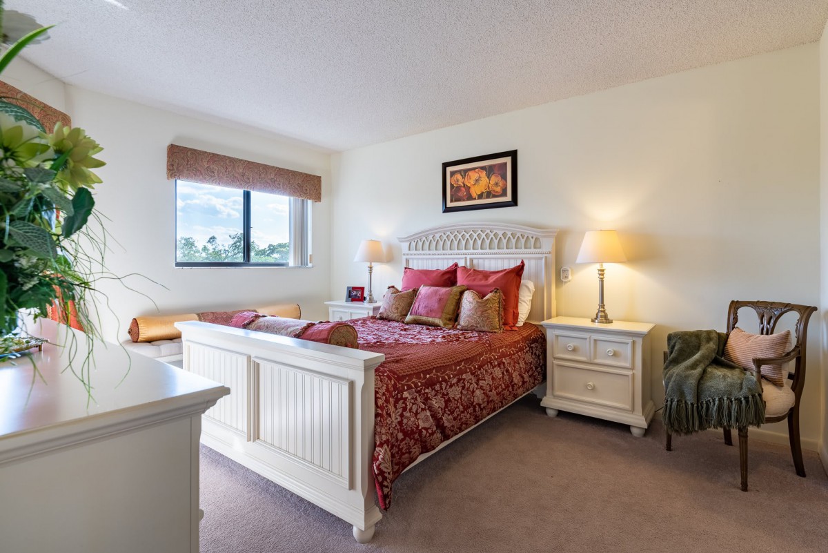 A cozy bedroom with a decorative bedspread, elegant furniture, and warm lighting.