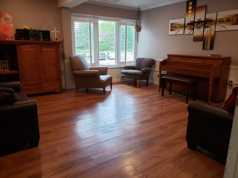 A cozy living room featuring wooden floors, a piano, and comfortable seating by the window.