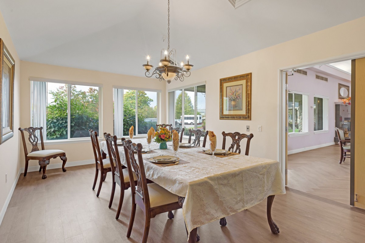 A well-lit dining room with a large table, multiple chairs, and a chandelier.