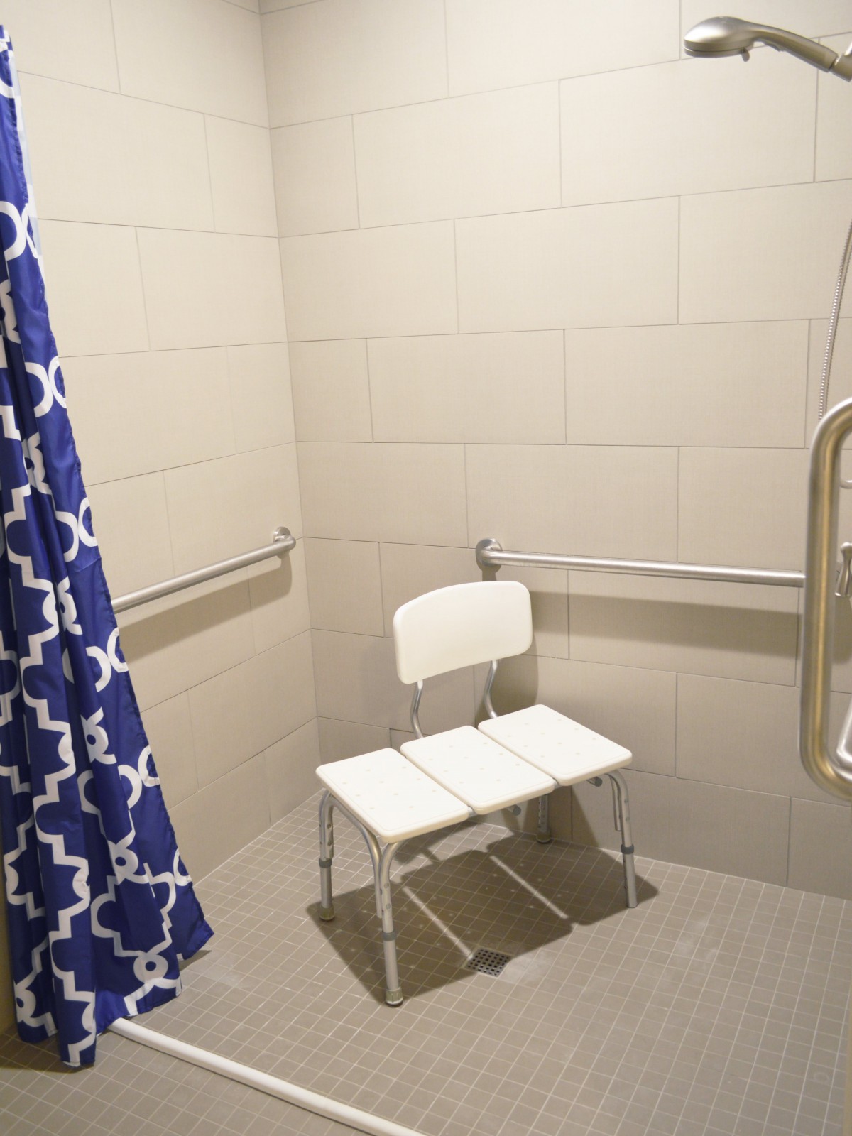 An accessible shower with a chair and grab bars for safety.