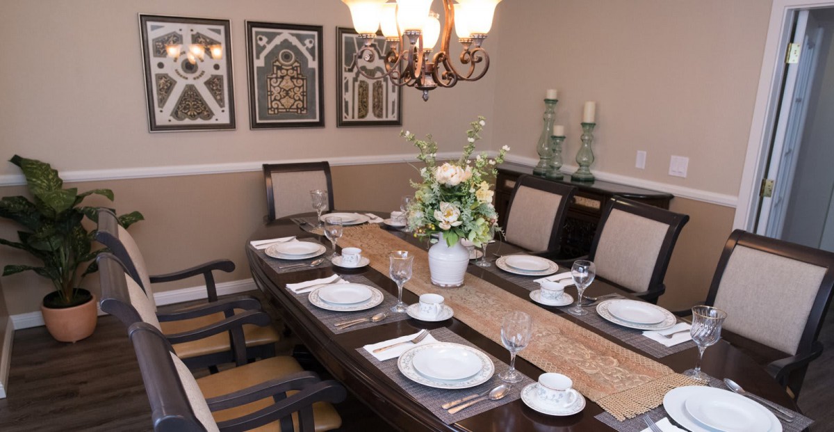 An elegantly set dining table with floral centerpiece and artistic wall decor.