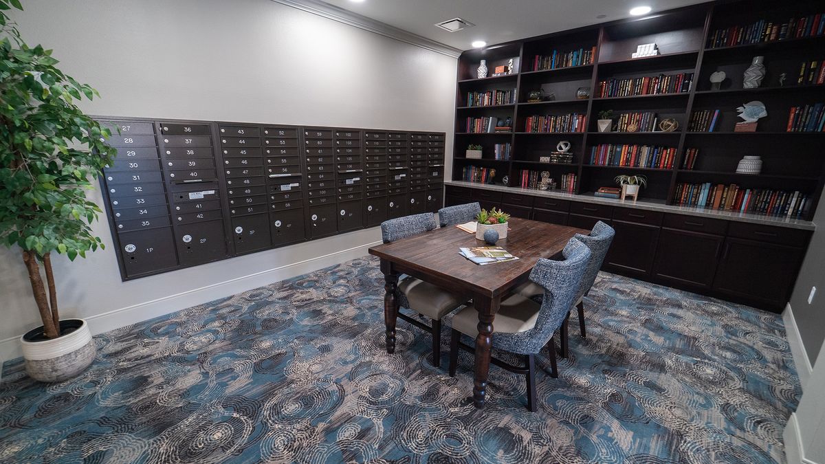 A cozy library room featuring a table with chairs surrounded by bookshelves and card catalogs.