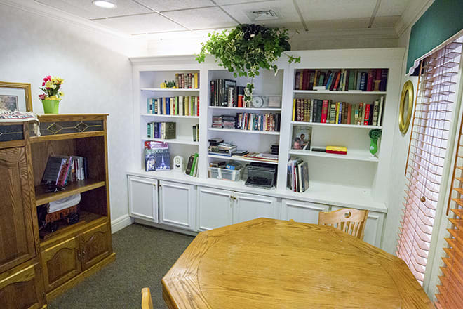 A cozy library corner with a wooden table and a well-stocked bookshelf.