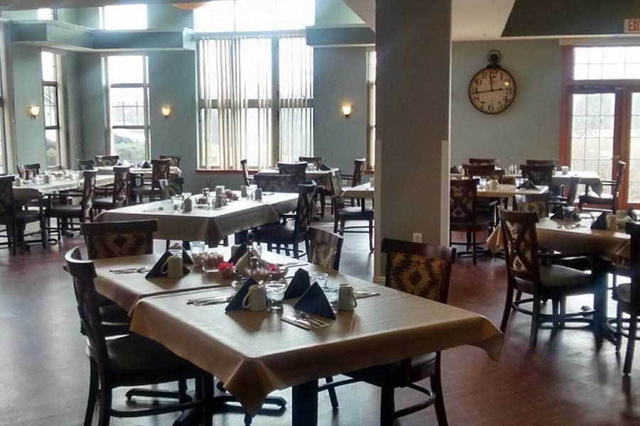 An empty restaurant dining area with neatly arranged tables and chairs.