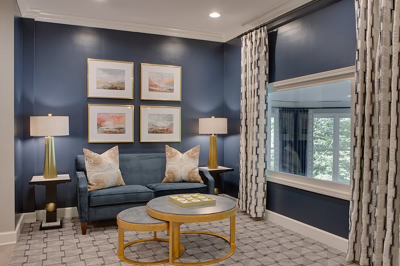 A stylish living room with blue walls features a cozy sofa, decorative pillows, and elegant artwork.
