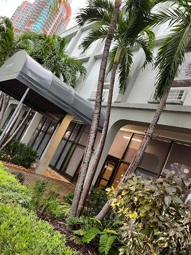 A modern building entrance framed by lush palm trees.