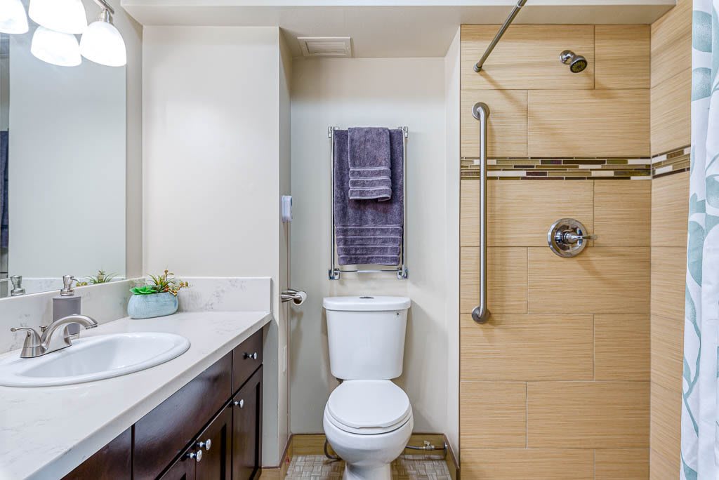 A modern bathroom featuring a sink, toilet, and shower area with neatly hung towels.