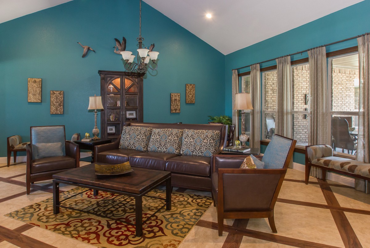 A cozy living room with teal walls featuring a comfortable seating arrangement, a wooden coffee table, and decorative elements.
