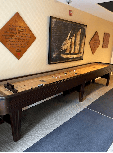 A shuffleboard table set against a wall adorned with nautical-themed artwork.