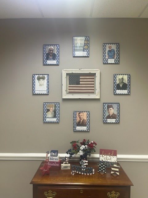 A wall display featuring framed photographs and an American flag as a tribute to military personnel.