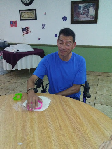 A man sitting in a wheelchair, engaged in an activity at a table.