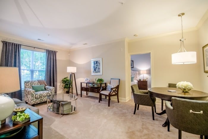 A modern and cozy living room with adjacent dining area, featuring elegant furniture and ample natural light.