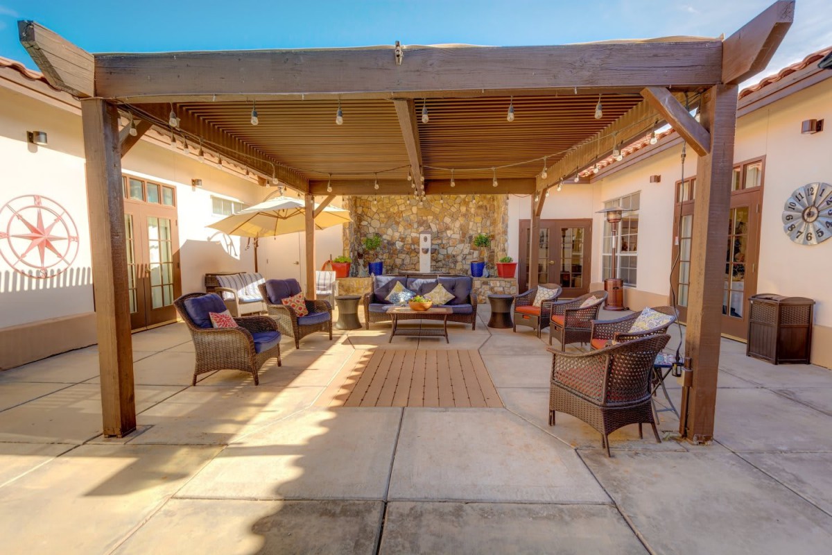 A spacious and inviting patio with comfortable seating under a pergola, perfect for outdoor gatherings.