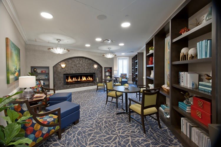 A cozy library interior featuring a fireplace, comfortable seating, and bookshelves.