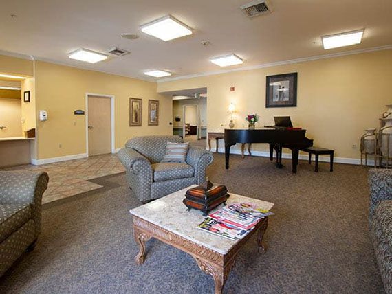 A cozy lobby area featuring a piano, comfortable seating, and a coffee table with magazines.