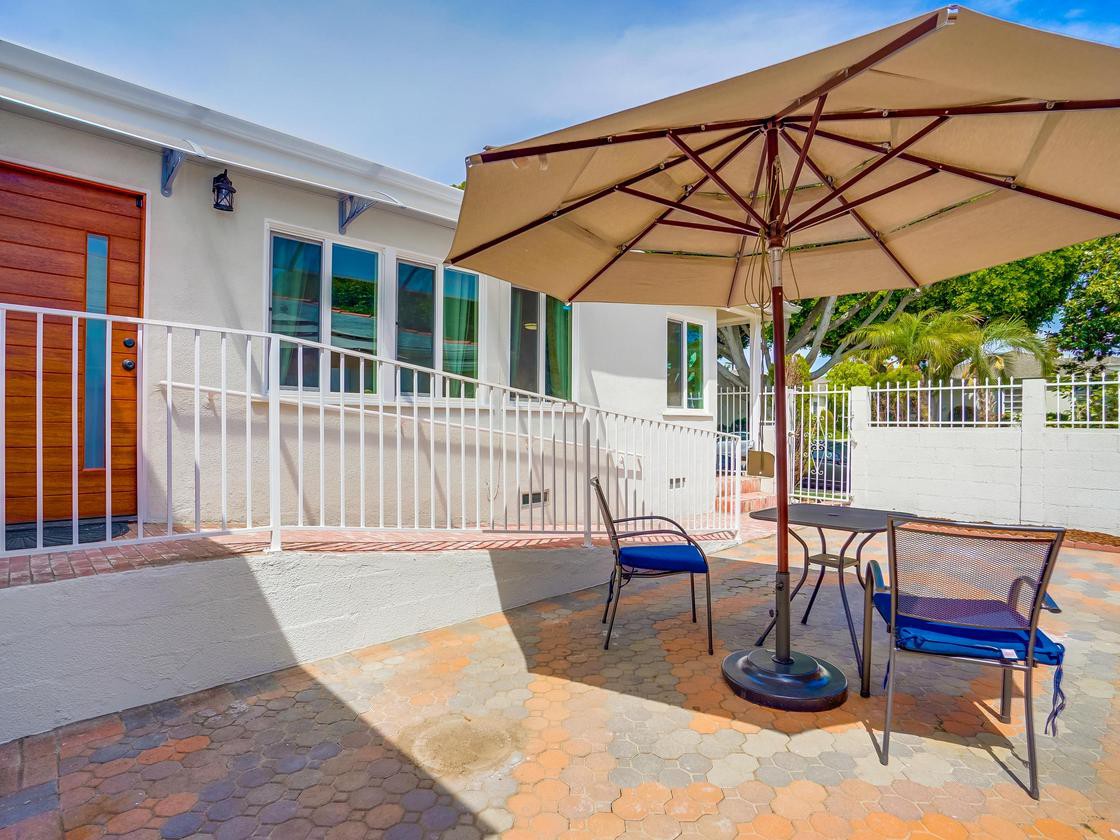 A sunny patio with an umbrella-shaded table and chairs.