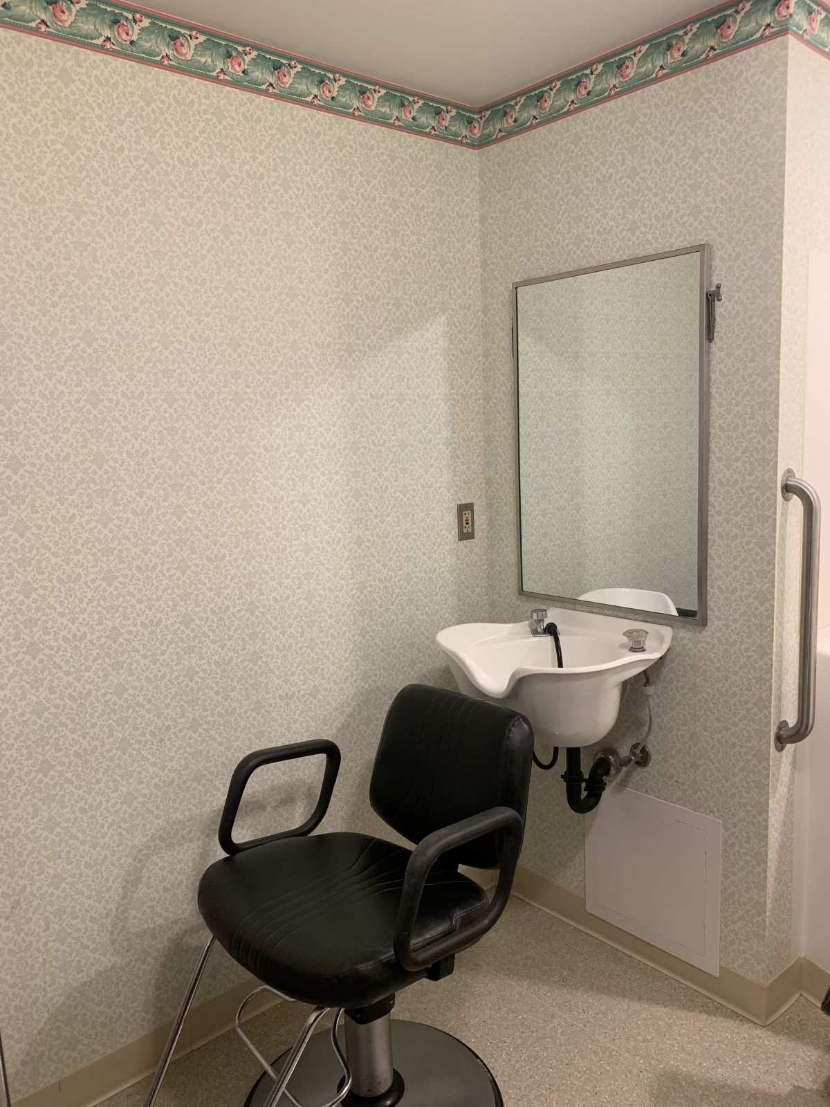 A minimalist room featuring a chair, sink, and mirror.