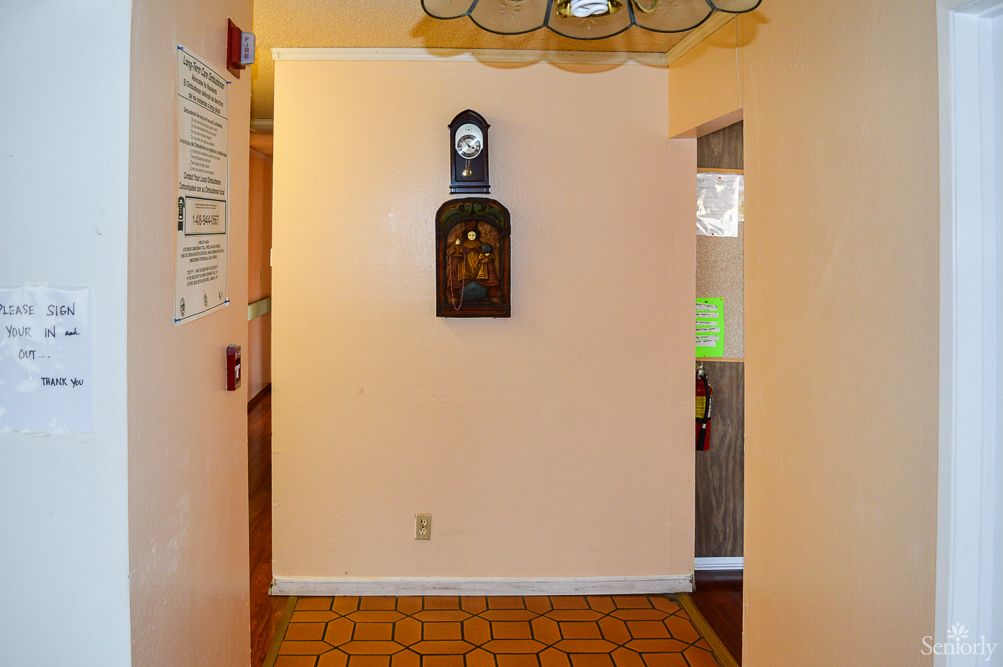 A hallway with a wall clock and tiled floor.