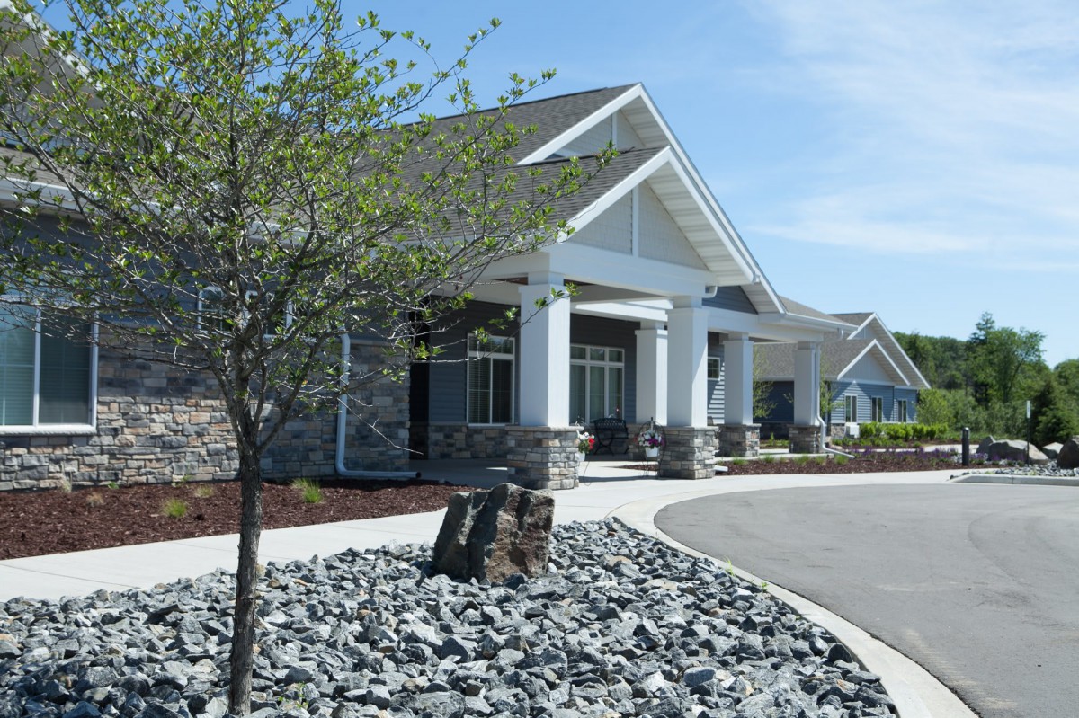A modern building entrance with stone landscaping and a tree in the foreground.