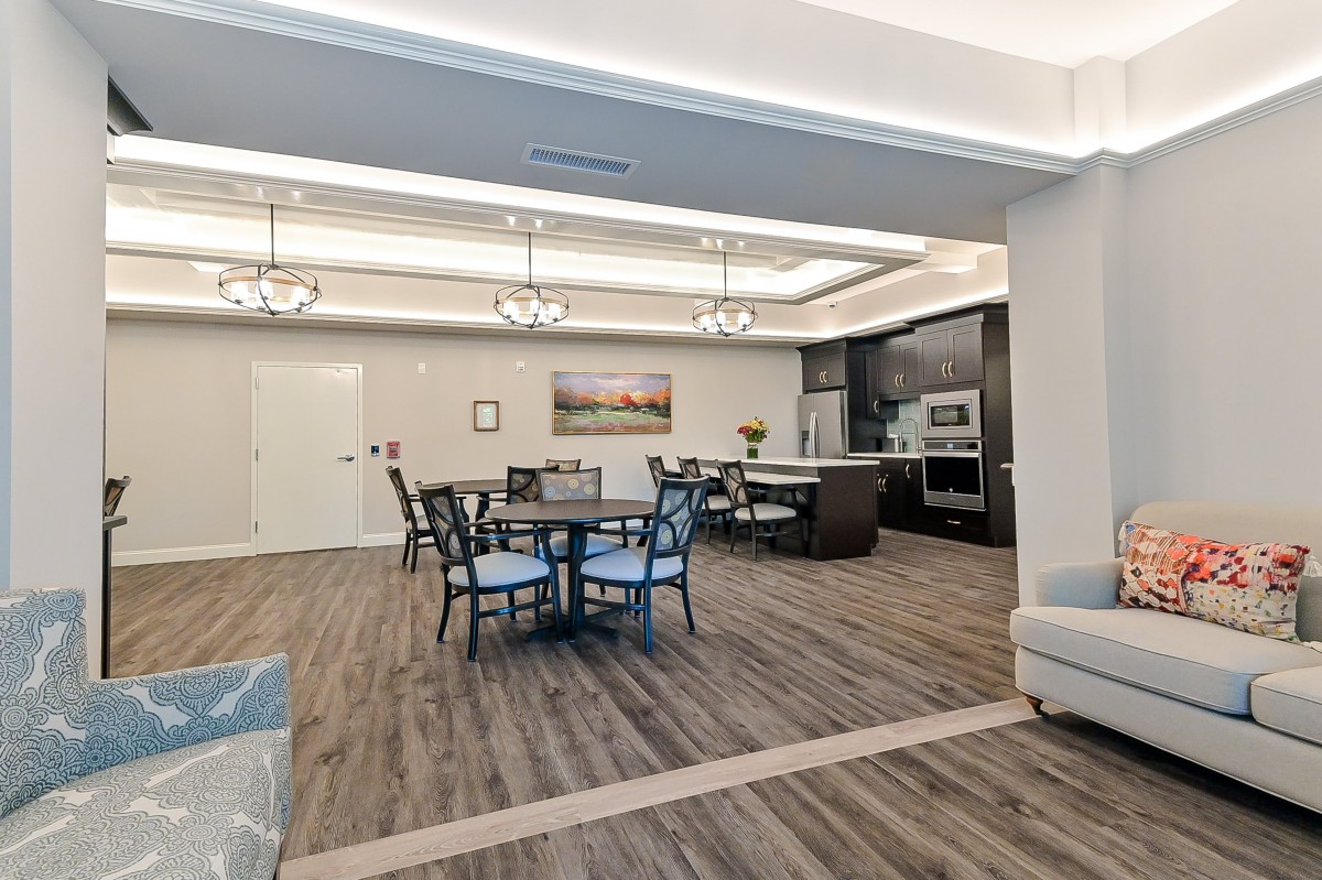 Modern interior featuring an open kitchen and dining area with elegant chandeliers and hardwood flooring.