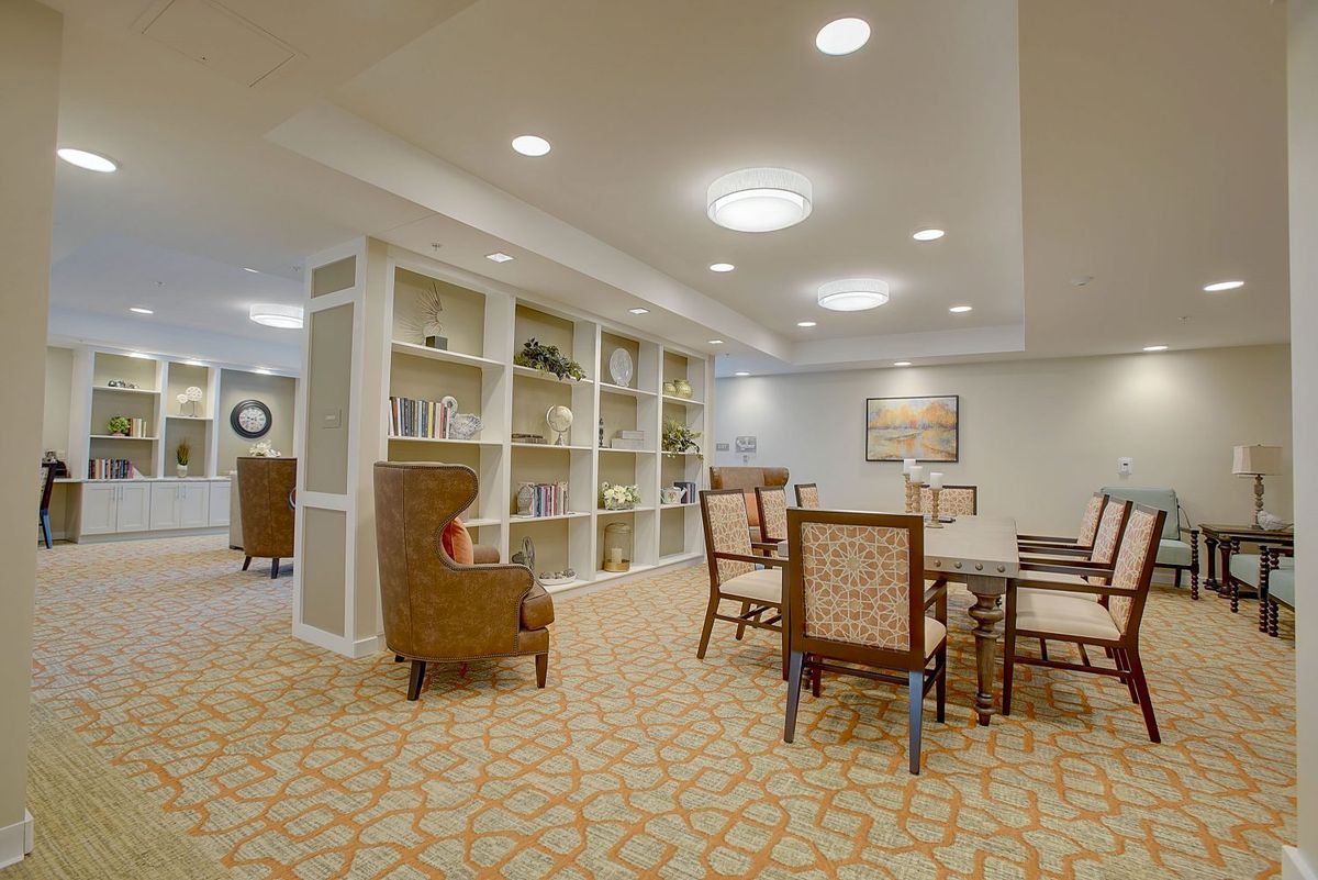 A cozy library seating area with bookshelves and comfortable chairs, elegantly lit by ceiling lights.