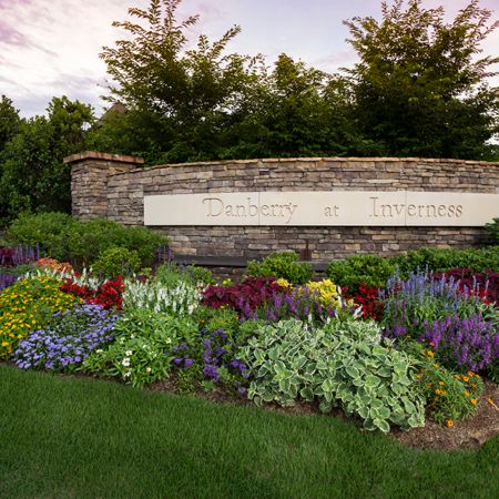 A beautifully landscaped garden with a variety of colorful flowers in front of a stone wall sign.