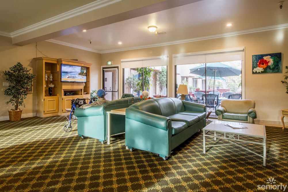 A bright and spacious living room featuring comfortable sofas, a television, and large windows.