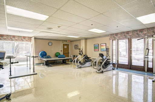 A well-equipped rehabilitation gym featuring exercise machines and therapy mats.