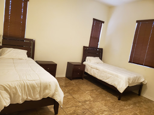 A cozy bedroom featuring two neatly made twin beds with wooden frames and illuminated by natural light from the windows.