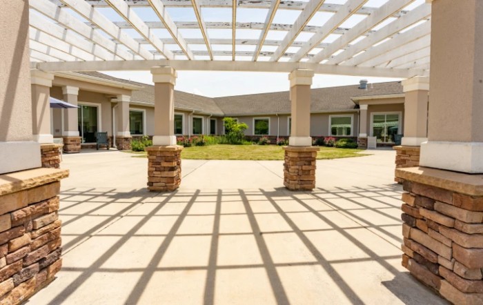A sunlit courtyard with a pergola providing shade over the patio.