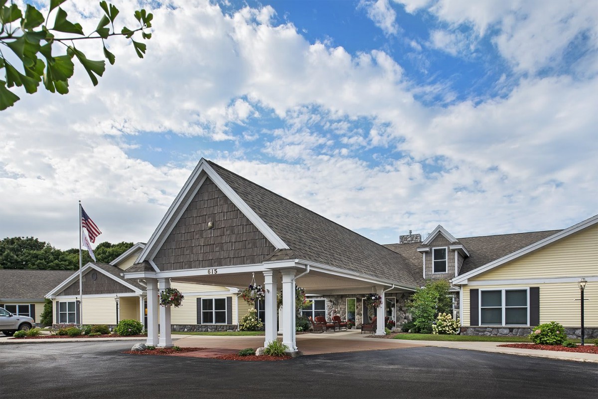 A residential building with a pitched roof and covered entrance under a partly cloudy sky.