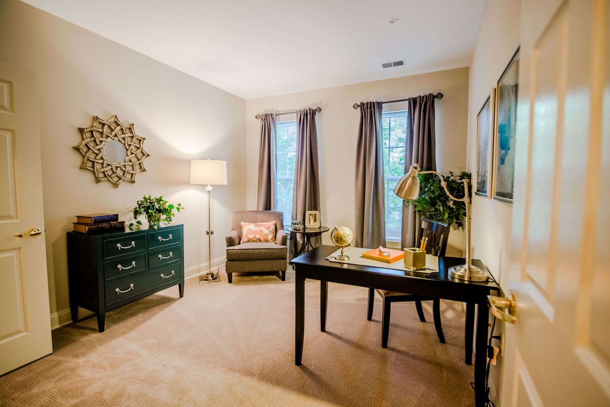 A cozy home office with a desk, chairs, and decorative elements.