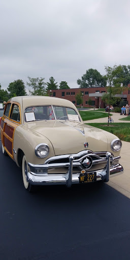 A beautifully restored vintage Ford station wagon with classic wood paneling on display at a car show.