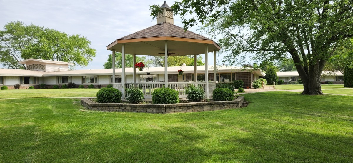 A charming gazebo surrounded by lush greenery and a well-manicured lawn.